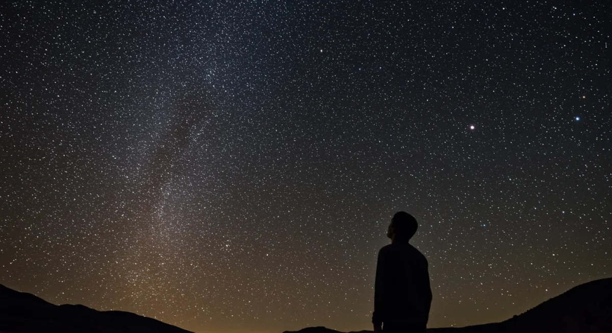 Pessoa contemplando o céu estrelado, inspirando paz e reflexão espiritual.