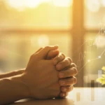 Pessoa orando com as mãos juntas, em luz dourada, simbolizando esperança e conexão divina para a prosperidade.