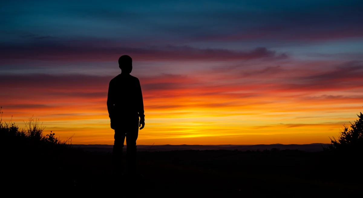 Pessoa contemplando o pôr do sol em um gesto de gratidão a Deus pela beleza da criação.