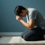 Pessoa orando ajoelhada, mãos unidas, em um ambiente sereno e iluminado, simbolizando esperança e consolo em momentos de dificuldade.