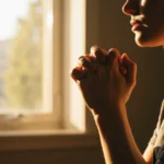 Pessoa orando em ambiente sereno com luz da manhã, simbolizando a oração matinal.